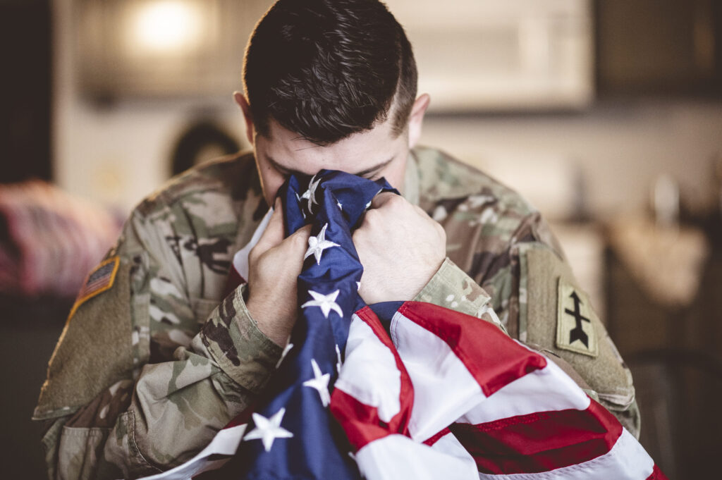 Veteran embracing the American flag, receiving addiction recovery support and treatment