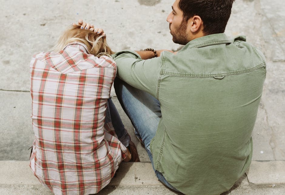 Man talks to woman leaning forward whole dealing with an alcohol withdrawal headache.