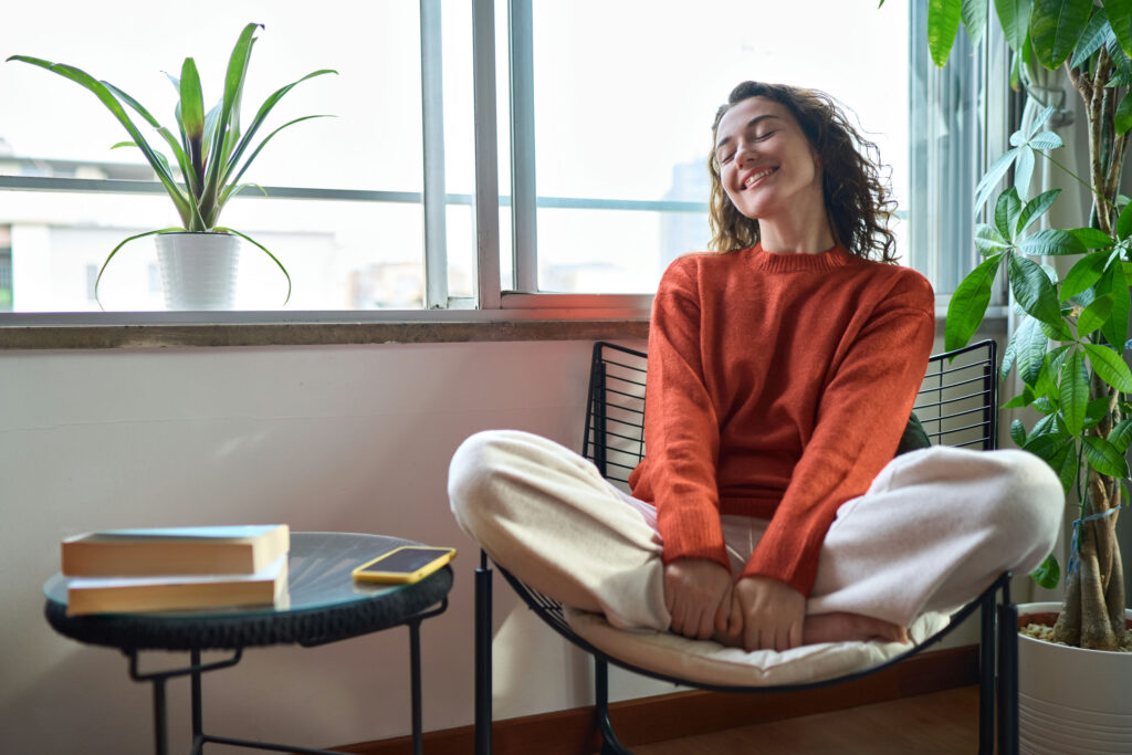 Woman smiling while sitting on a chair with crossed legs.