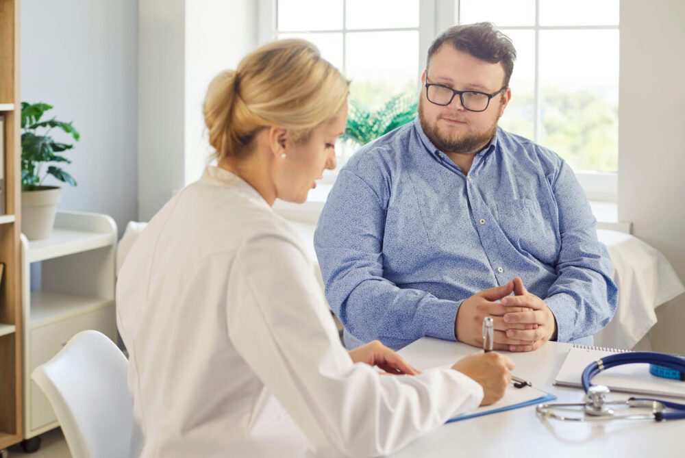 Man listens while woman reads out treatment options for addiction.