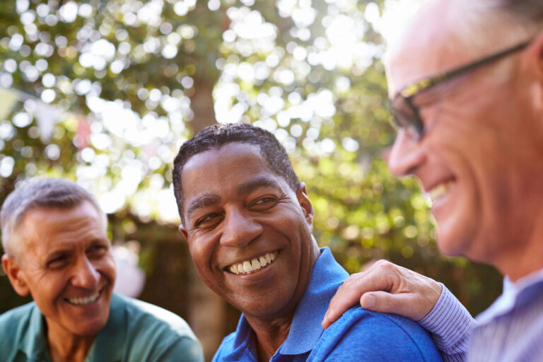 Two older men brace shoulders and reassure man learning how to detox from drugs safely.
