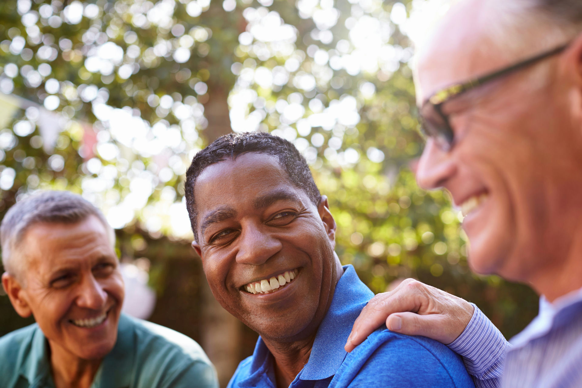 Two older men brace shoulders and reassure man learning how to detox from drugs safely.